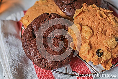 Oatmeal cookie milk cookie and chocolate chip nut cookie on grate metal red and white napkin black background. Stock Photo