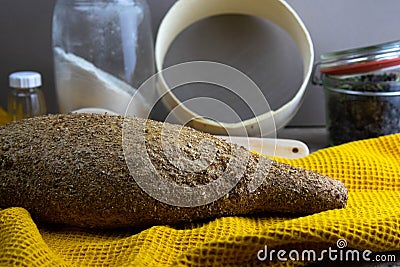 Oatmeal diet bread on a yellow towel in the background is satiated for flour, a jar of flour, spices and a spoon Stock Photo