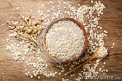 Oatmeal flakes and ears of oat on wooden table Stock Photo