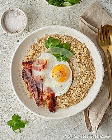 Oatmeal, fried egg, fried bacon. Intuitive conscious food, vertical Stock Photo