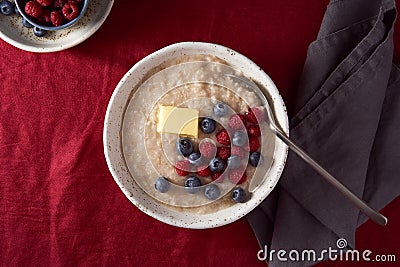 Oatmeal porridge with blueberry, bilberry on dark red cranberry linen tablecloth. Stock Photo