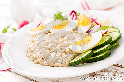 Oatmeal porridge with boiled egg and vegetable salad with fresh radish, cucumber and lettuce. Healthy dietary breakfast Stock Photo