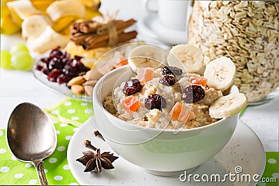 Oatmeal porridge with dried fruits, cranberries, bananas and spices. Jar of oatmeal on background. Stock Photo