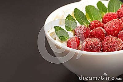 Oatmeal with strawberries, whipped cream and mint leaves, close-up Stock Photo