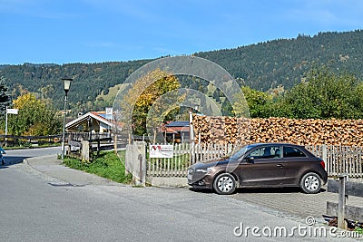 OBERAMMERGAU, GERMANY - OKTOBER 09, 2018: Car and pile of firewood besides of a village house in the Alps in autumn Editorial Stock Photo
