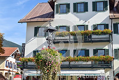 OBERAMMERGAU, GERMANY - OKTOBER 09, 2018: Vintage lantern with flowers on the balcony of old building under sun Editorial Stock Photo