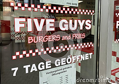 View on restaurant window with lettering of five guys burgers and fries chain with opening hours Editorial Stock Photo