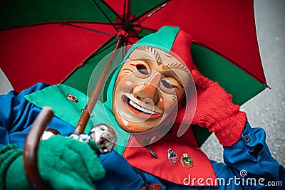Carnival fool in red-green robe and umbrella rests on the floor Editorial Stock Photo