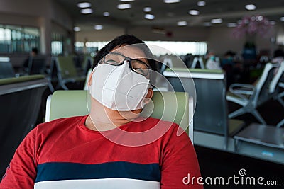 Obese Asian man wearing protective face mask sit sleeping on seat at airport Stock Photo