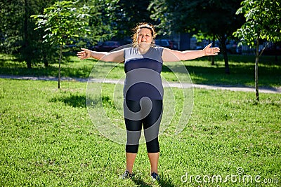 Obese European woman doing morning exercises in nature. Stock Photo