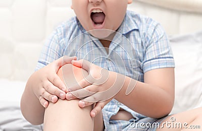 Obese fat boy suffering from knee pain and sit on bed Stock Photo