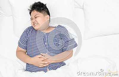 Obese fat boy suffering from stomachache and lying on bed Stock Photo