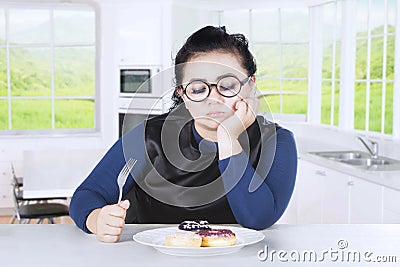 Obese female feels gorged with donuts Stock Photo