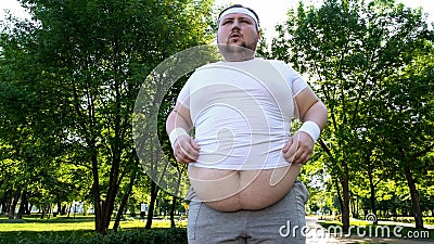 Obese person hardly doing exercises in city park, personal training program Stock Photo