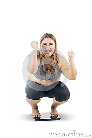 Obese woman squat down on the weight scales Stock Photo