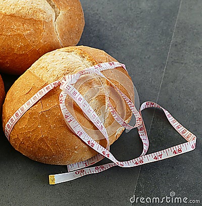 Obesity and whole wheat bread, tape measure wrapped in a large bread Stock Photo