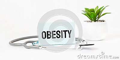 OBESITY word on notebook,stethoscope and green plant Stock Photo