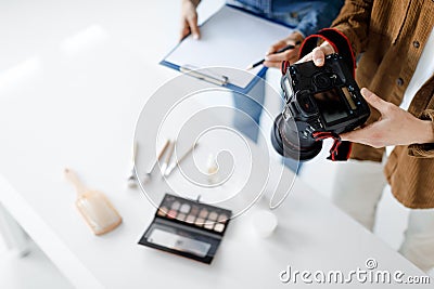 Object photography concept. Male photographer taking photo of cosmetic products, working in team with assistant Stock Photo