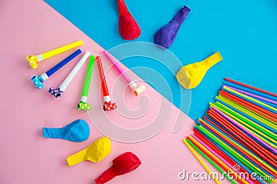 Objects for celebrating a birthday lie on a blue and pink background. Balloons, tubes for cocktails and pipes, whistles and Stock Photo