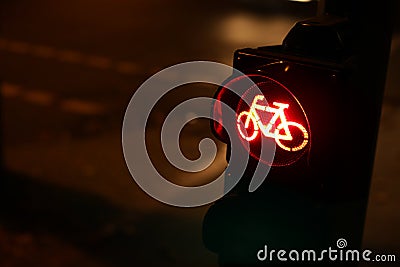 oblique closeup view on traffic light for a cycling lane showing red bicycle symbol at night with car lights in background Stock Photo