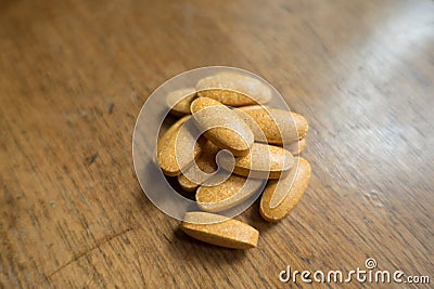 Oblong multivitamin dietary supplement tablets on wood Stock Photo