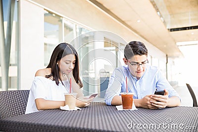 Obsessed Couple Using Smartphones In Shopping Mall Stock Photo