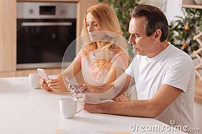 Obsessed mature couple showing addiction to the gadgets at home Stock Photo