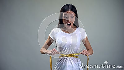 Obsessed woman tightening measuring tape on her waist desire to be slim, bulimia Stock Photo