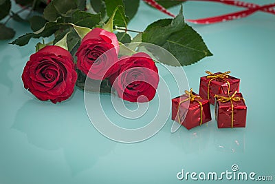Occasional beautiful red roses with tiny boxes of gifts on the background Stock Photo