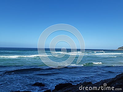 Ocean with blue skies from rocky shore Stock Photo