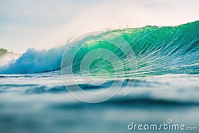 Crashing perfect wave in ocean. Breaking green barrel wave with sunset light Stock Photo