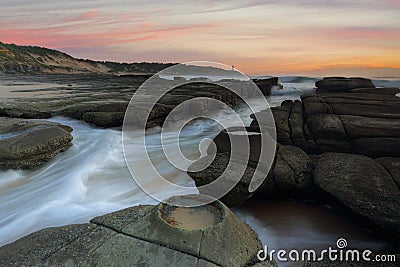 Ocean flowing in and out of the rock chasm Norah Head Stock Photo