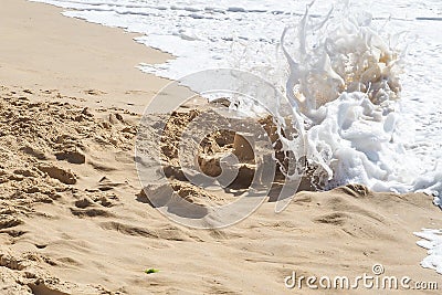 Ocean's waves destroy kid's sand castle Stock Photo