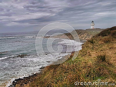 An ocean shore and Waipapa Point lighthouse in the Catlins area of the South Island of New Zealand Stock Photo