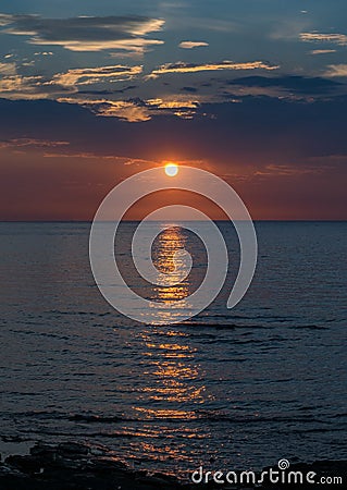 Ocean sunset dark sky horizon clouds bloody sun Stock Photo