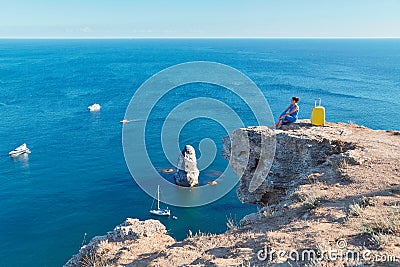 Ocean view and floating yacht in water. Lady enjoying seascape on cliff. Remote office and travel time idea, copy space Stock Photo