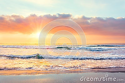 Ocean wave on the beach at sunset time, sun rays Stock Photo