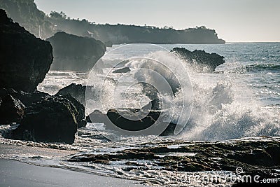 Ocean waves crashing onto the rocks in the sunset Stock Photo