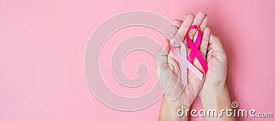 October Breast Cancer Awareness month, adult Woman hand holding Pink Ribbon on pink background for supporting people living and Stock Photo