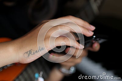 October 22nd 2018 in Denpasar, Bali, Indonesia - Young artist & musician woman using mobile phone with her own tattoo name on it. Editorial Stock Photo