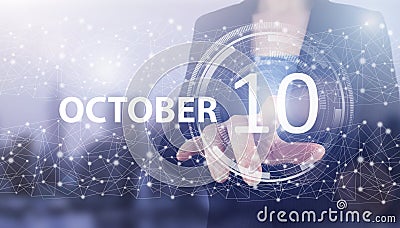 October 10th. Day 10 of month, Calendar date. Hand click luminous hologram calendar date on light blue town background. Autumn Stock Photo