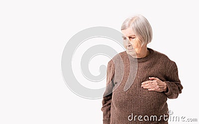 Octogenarian old lady complains of pain in her heart. She keeps her hand on her chest in the heart area. Stock Photo