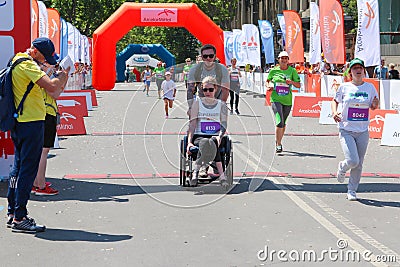Handicapped woman in marathon on a wheelchair. Handicapped runner on marathon Editorial Stock Photo