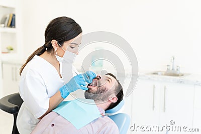 Odontologist Examining Teeth Of Mid Adult Man Stock Photo