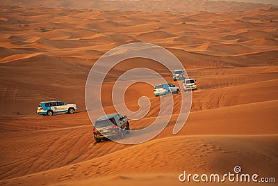 Off-road adventure with SUVs driving in Arabian Desert at sunset. Traditional entertainment for tourists with vehicle bashing thro Editorial Stock Photo