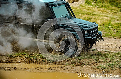 Off road jeep expedition to the villages on mountain road. Classic 4x4 car crossing water with splashes on muddy road Stock Photo