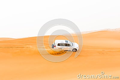 Off-road SUV vehicle speeding through sand dunes in the Arabian desert Stock Photo