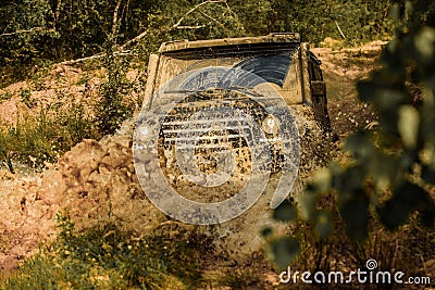 Off-road vehicle goes on the mountain. Mudding is off-roading through an area of wet mud or clay. Tracks on a muddy Stock Photo