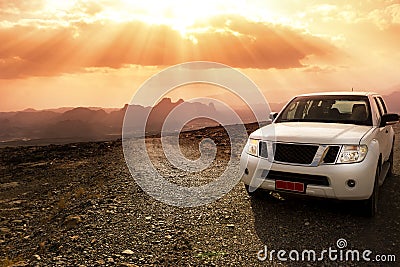 Off-road vehicle on the Jebel Shams mountains and cloudy sky with amazing sunrays Stock Photo