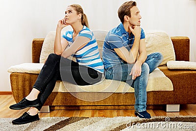 Offended couple sitting back to back on sofa Stock Photo